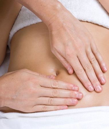 Woman having abdomen massaged as part of a colonic irrigation treatment